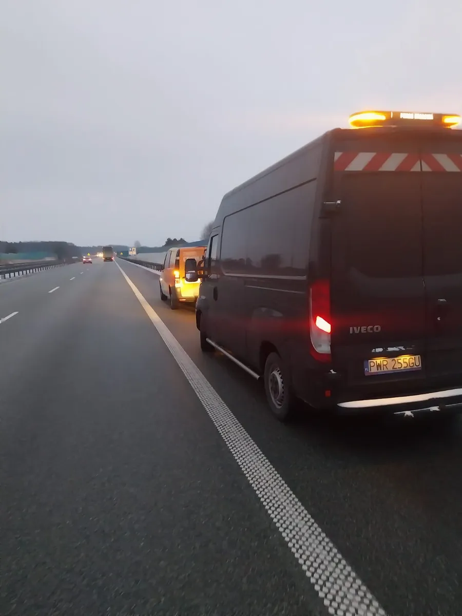 Bus pomocy drogowej z lampami ostrzegawczymi na pasie awaryjnym autostrady