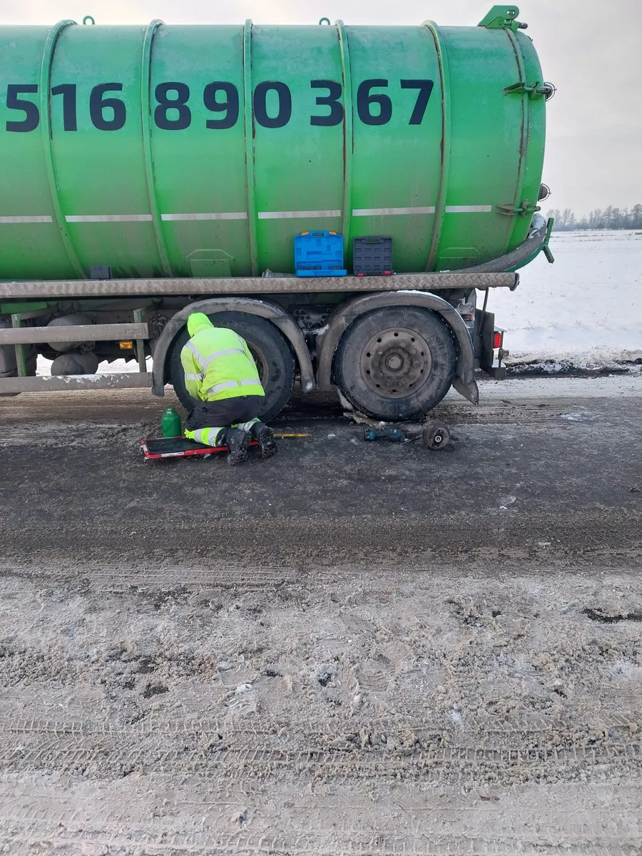 Mechanik w odblaskowej kurtce naprawiający pojazd ciężarowy zimą